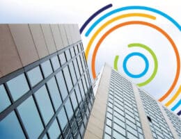 Zakelijk kantoorgebouw met reflecterende ramen, met daarboven het logo van Binnenklimaattechniek verwerkt in kleurrijke cirkels